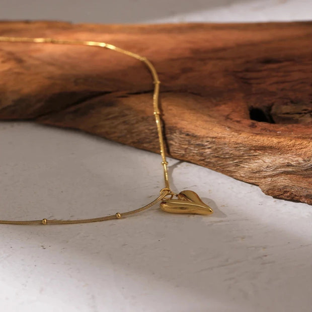  Overhead shot of the heart pendant choker necklace laid flat on a marble surface, showcasing its simplicity.